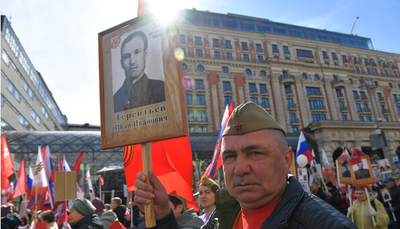 9일 러시아 수도 모스크바에서 시민들이 참전용사의 사진을 들고 퍼레이드에 참가하고 있다. (사진=신화통신 제공)